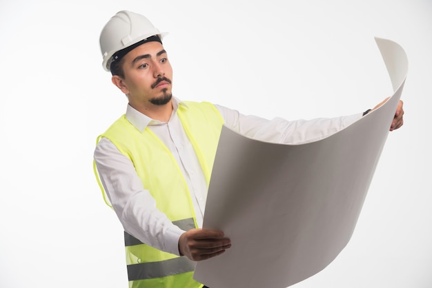 Free photo engineer in uniform holding and reading the architectural plan of the construction.