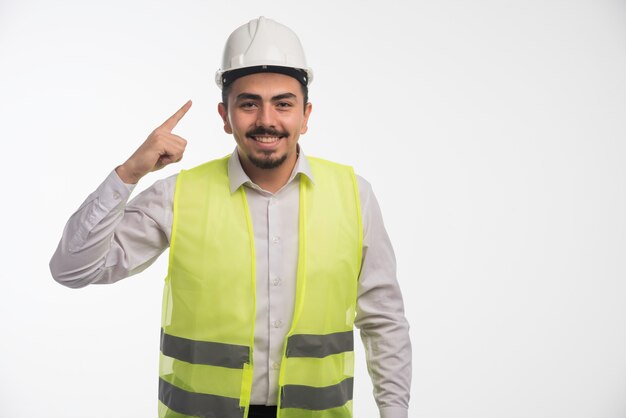 Engineer in uniform pointing to his helmet. 