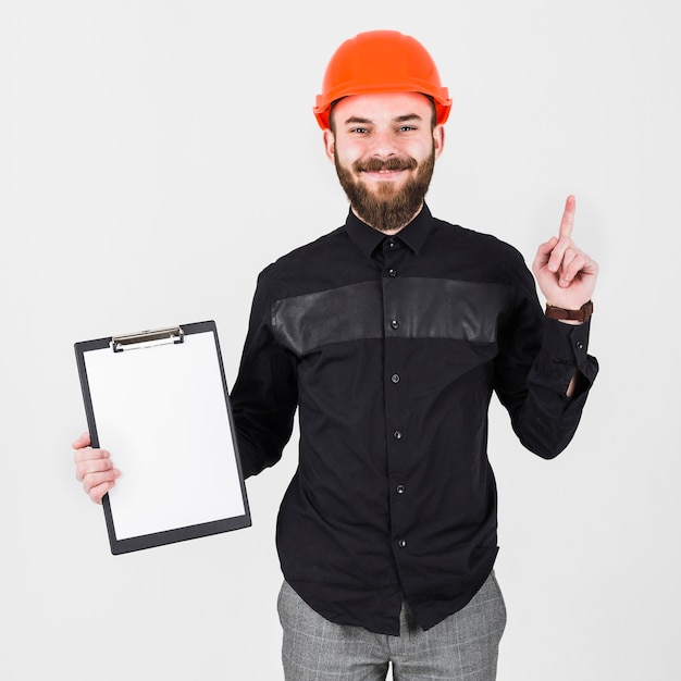 An engineer wearing hardhat holding clipboard gesturing