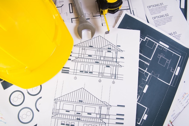 Engineer workplace with blueprints, protractor and safety helmet.