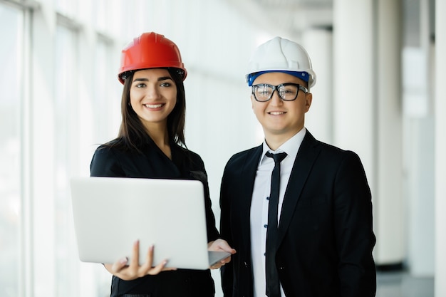 Free photo engineering and architecture concept. engineers working on a building site holding a laptop, architect man working with engineer woman inspection in workplace for architectural plan