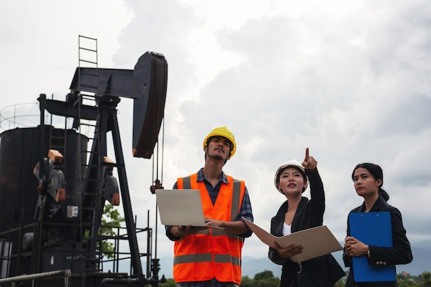 Free photo the engineering team stands beside working oil pumps with a sky .