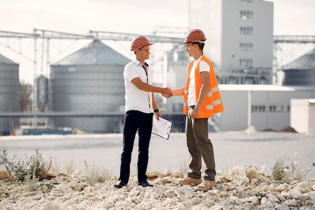 Free photo engineers in helmets standing by the factory