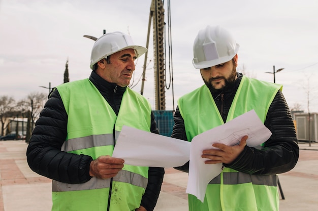 Foto gratuita ingegneri che esaminano le bozze sul cantiere