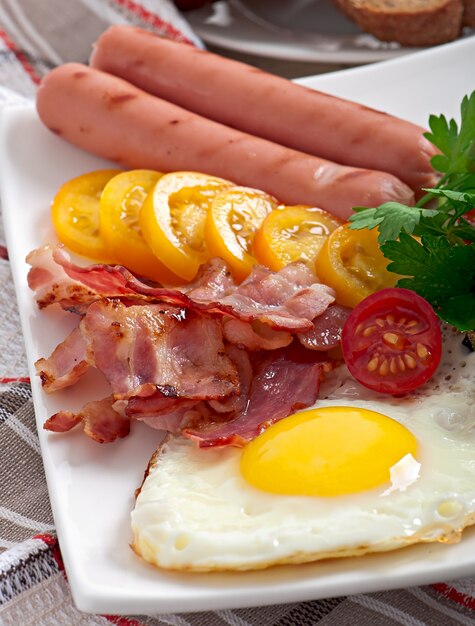 English breakfast - fried eggs, bacon, sausages and toasted rye bread