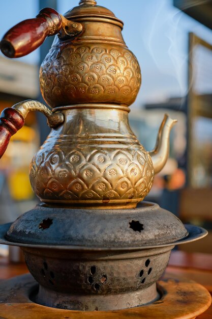 Engraved copper Turkish teapot selective focus Turkish traditional teapot with double teapots on a stand with coals in a cafe vertical shot steam rising from the teapot spout