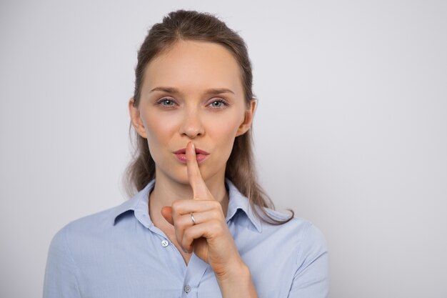 Enigmatic woman showing shh gesture