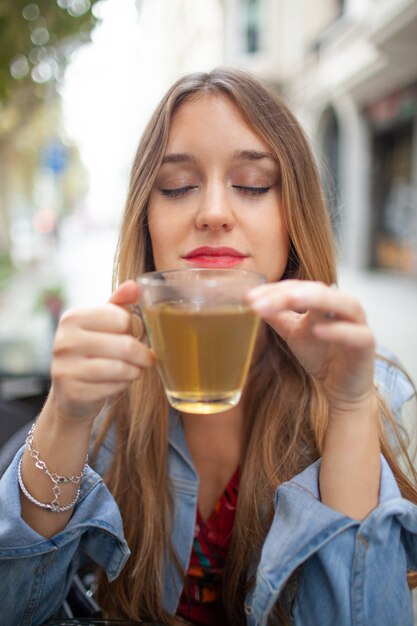 Enjoyable young woman smelling scented green tea