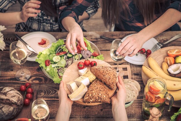 Enjoying dinner with my friends. Top view of a group of people dining together, sitting at a rustic wooden table, the concept of celebration and healthy home-cooked food