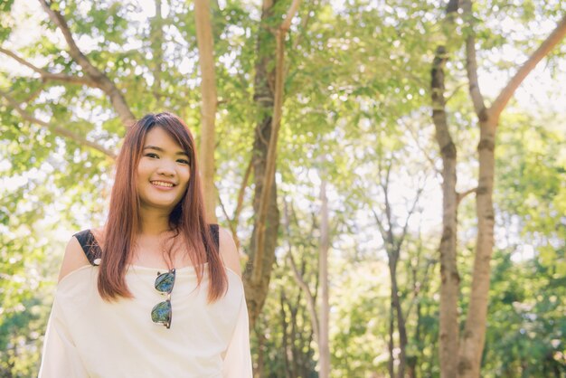 Enjoying the nature. Young asian woman arms raised enjoying the fresh air in green forest.