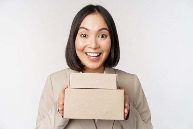 Enthusiastic asian businesswoman giving customer order boxes standing against white background