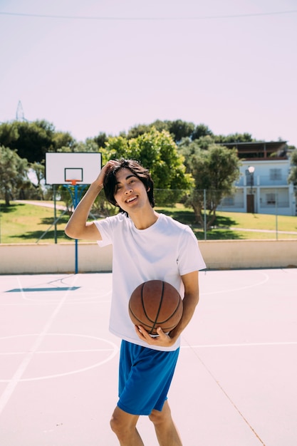 Enthusiastic Asian teen student playing basketball