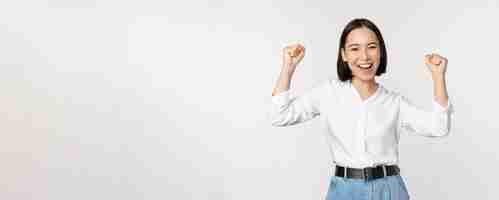 Free photo enthusiastic asian woman rejoicing say yes looking happy and celebrating victory champion dance fist