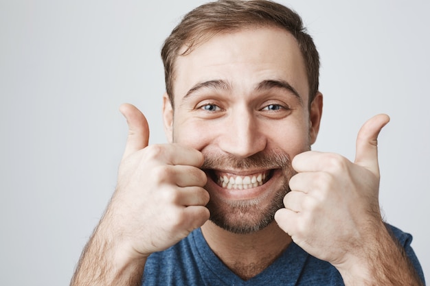 Бесплатное фото Восторженный бородатый парень показывает палец вверх счастливым