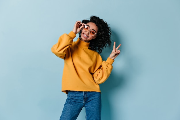 Enthusiastic curly woman showing peace sign