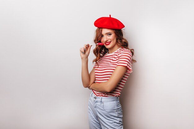 Enthusiastic female model in red beret holding candy.  excited white girl with lollipop.