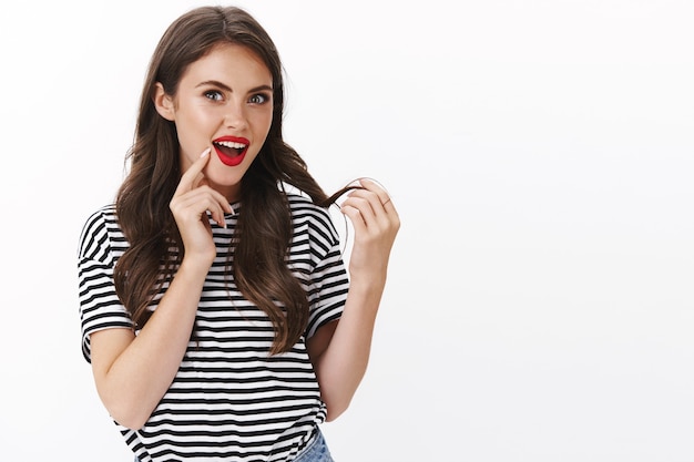 Enthusiastic glamour fashionable alluring woman delighted new haircut, wear makeup red lipstick, touch curl open mouth impressed and delighted, satisfied good haircare product, white wall