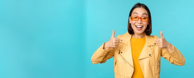 Enthusiastic korean girl looks excited and shows thumbs up approves smth awesome excellent choice an