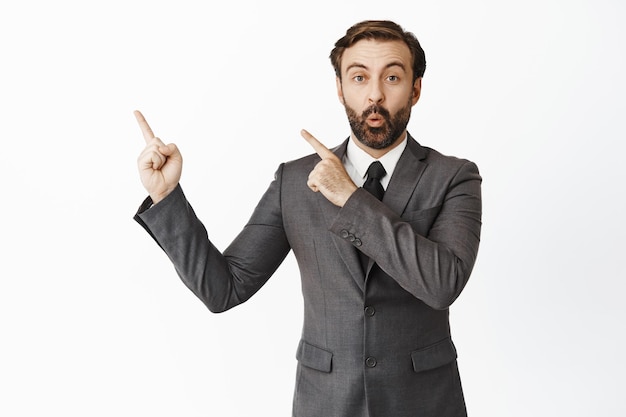 Free photo enthusiastic salesman say wow pointing at upper left corner advertisement showing diagram company name on copy space white background