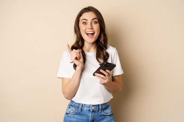 Enthusiastic woman holding smartphone and laughing, found smth online, concept of shopping and cellular technology