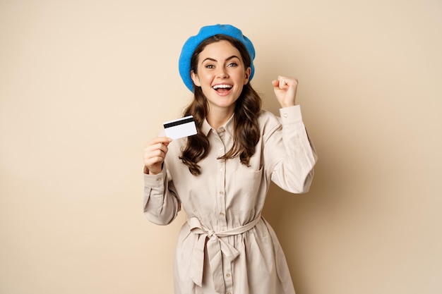 Free photo enthusiastic young woman yearning to go shopping, dancing with credit card and celebrating, laughing and smiling