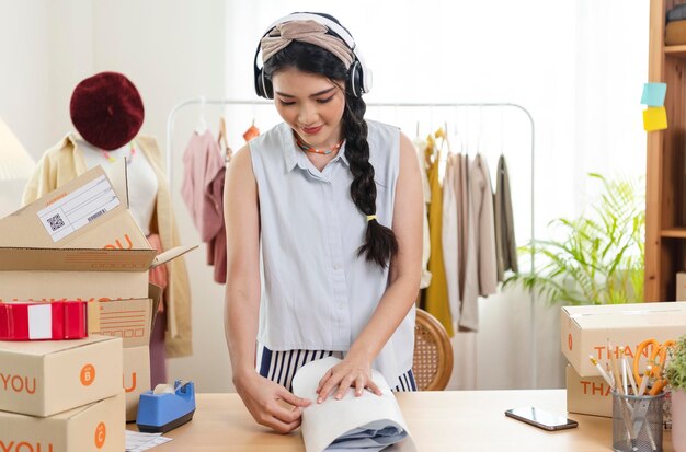 기업가 아시아 여성은 고객 창업 중소기업 소유자에게 옷 포장 주문을 판매합니다.