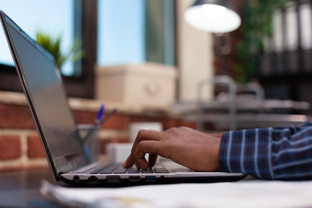 Entrepreneur hands composing email on laptop keyboard sitting at desk in marketing agency modern office. Detail view of freelancer fingers working on sales statistics on portable computer.