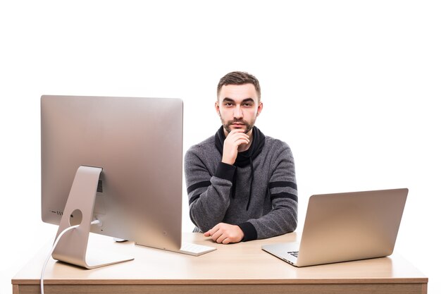 ノートパソコンとパソコンを持ってテーブルに座って、白で隔離のカメラを見ている起業家