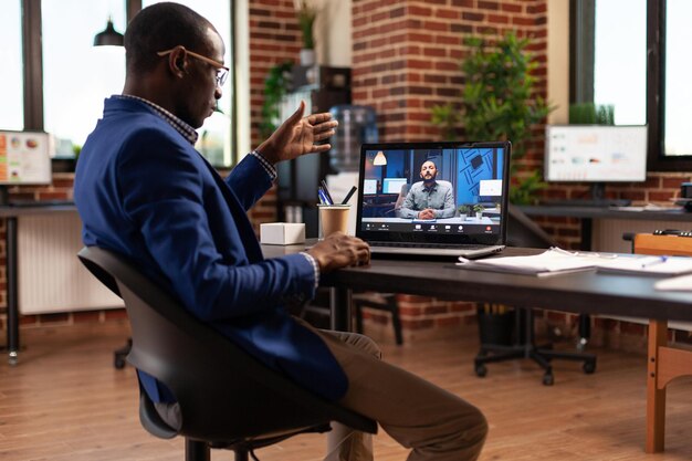 Entrepreneur using video call conference on laptop to talk to colleague in startup office. Business man attending online teleconference meeting with person to discuss project and strategy.