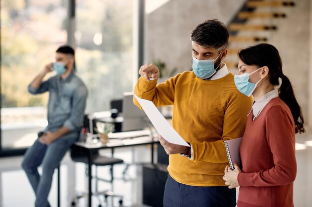 Entrepreneurs wearing face masks while examining business plans and working in the office