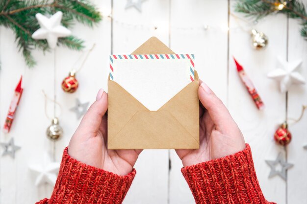 Free photo envelope and blank christmas card in female hands top view