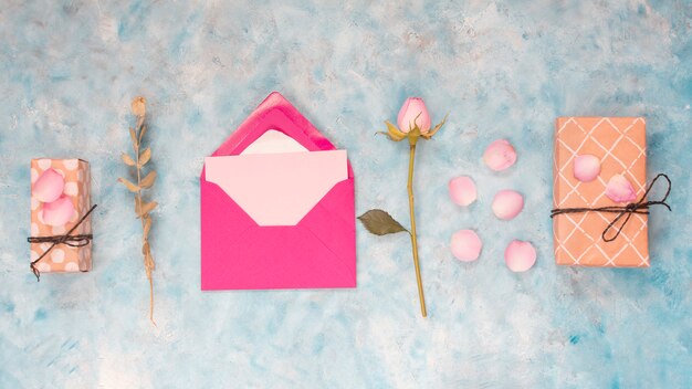 Envelope near present boxes, flower and petals 