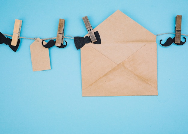 Envelope near tag, ornamental bow ties and mustaches on thread