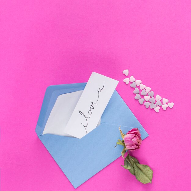 Envelope with paper with title near ornament hearts and flower