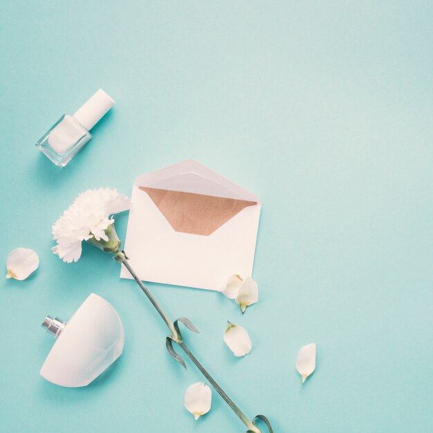 Envelope with white flower and perfume on blue table