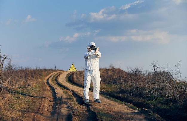 Эколог стоит на дороге с символом ядовитой опасности