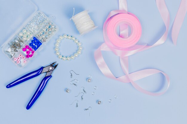 Equipment for making the hand made earrings with pink ribbon on blue background