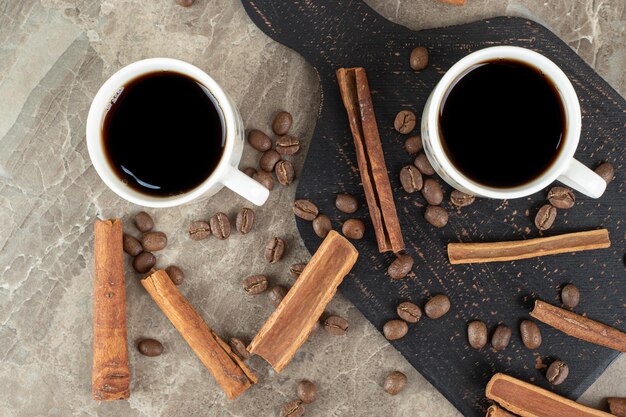 Espresso coffee, cinnamon sticks and coffee beans on marble surface