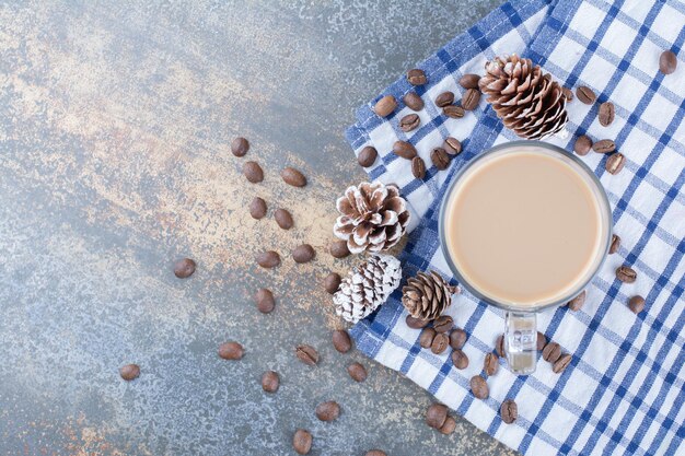Кофе эспрессо с шишками и кофейными зернами на скатерти. Фото высокого качества