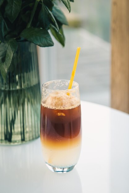 Espresso tonic in a glass with a yellow drinking straw