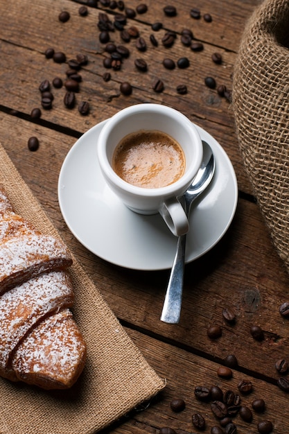 Foto gratuita caffè espresso con cornetto e semi di caffè
