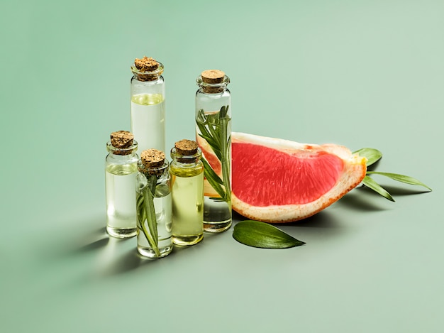 Essential oil in glass bottle with fresh, juicy grapefruit and green leaves-beauty treatment.