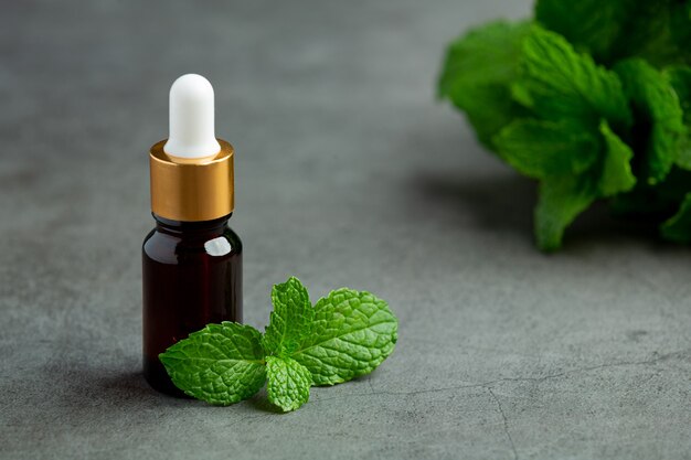 Essential oil of peppermint in bottle with fresh green peppermint