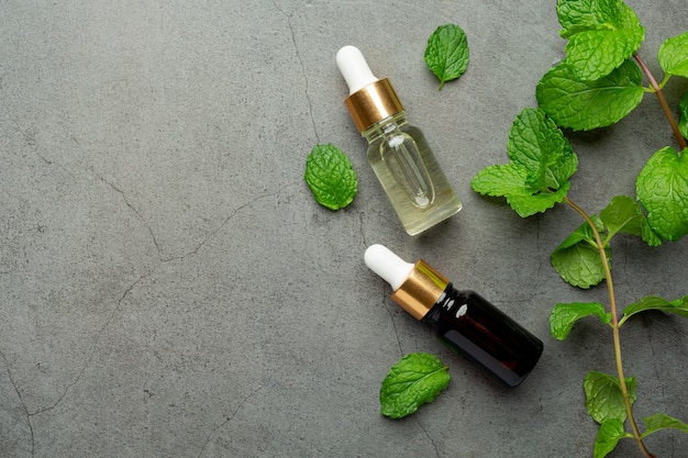 Essential oil of peppermint in bottle with fresh green peppermint