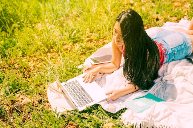 Ethnic brunette woman looking into laptop in glade