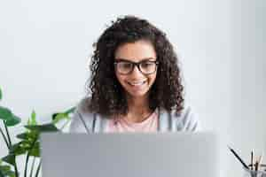 Free photo ethnic female employee with glasses working at laptop