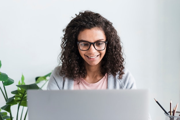 Ethnic female employee with glasses working at laptop