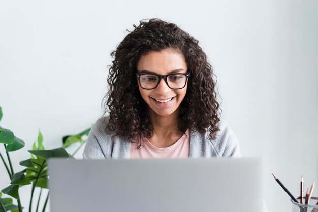 ethnic female employee with glasses working at laptop