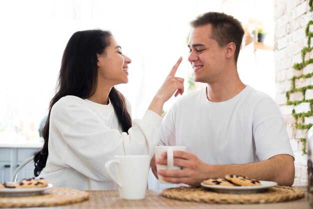 Ethnic female touching nose with hand of boyfriend