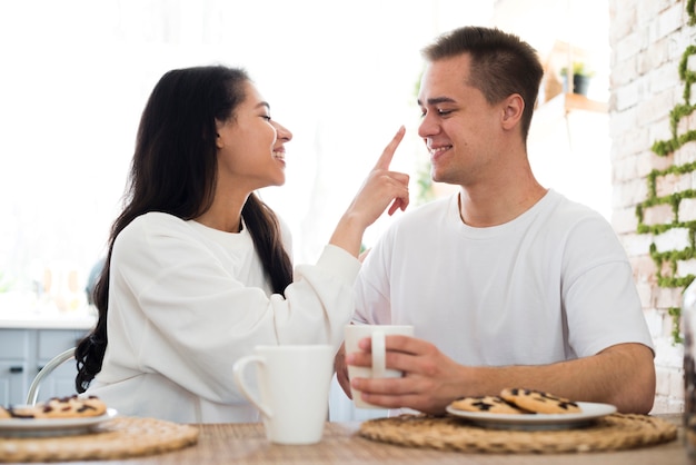 Ethnic female touching nose with hand of boyfriend